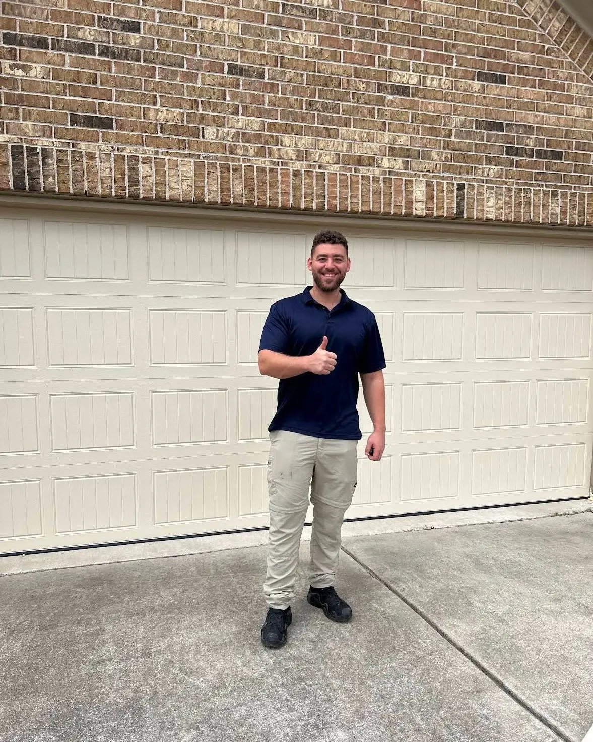 Tier One technician giving a thumbs up in front of a customer’s garage door